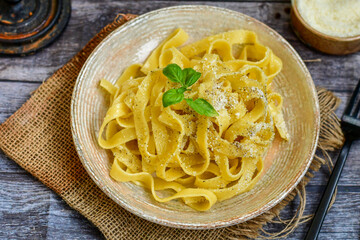 Italian food . Fresh home made  tagliatelle vegetarian  egg pasta  with ,parmesan cheese ,fresh parsley  and black pepper.Pasta cacio e pepe