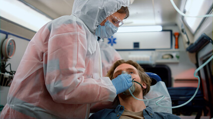 Emergency medical doctors giving first aid help to patient in ambulance car