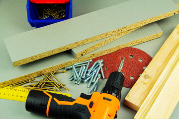 furniture assembly tools, screws, chipboard, screwdriver, ruler, sandpaper.