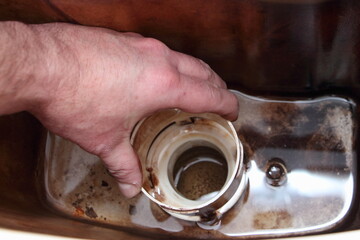 The plumber's hand remove the old dirty cork base from empty drain water tank closeup - DIY WC repair at home