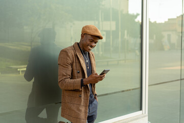 Hombre con expresión de felicidad mandando un mensaje de texto en la cristalera de la oficina.