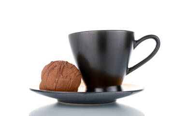Two sweet chocolate cookies on a ceramic saucer with a cup, close-up, isolated on white.