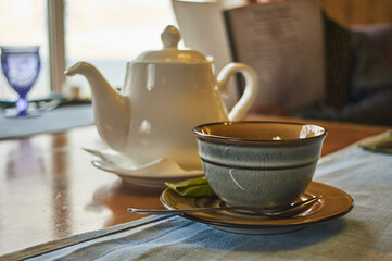 Tea pot with tea cup with spoon and sugar on the wooden brown  table