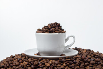 Coffee beans on a white background. A coffee cup full of coffee beans. Large serving of caffeine