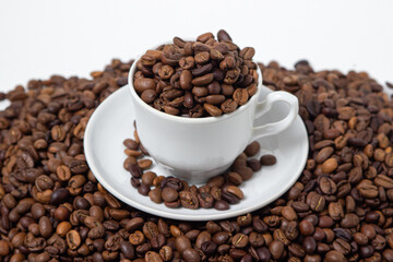 Fototapeta premium Coffee beans on a white background. A coffee cup full of coffee beans. Large serving of caffeine