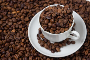 Coffee beans on a white background. A coffee cup full of coffee beans. Large serving of caffeine