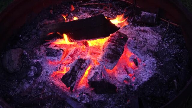 Logs in campfire outside in a pit; close up of exterior campfire, last log on fire before dying out. Orange flames, 621 
