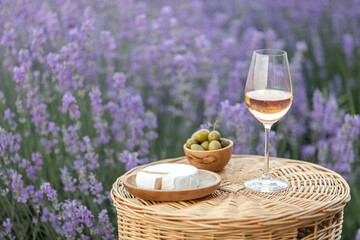 Glass of white wine in a lavender field. Violet flowers on the background.