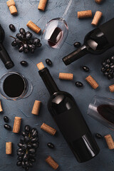 Wineglasses with red wine,black grape,wine corks and lying bottle on black stone desk. Top view.