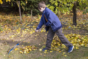 Kind arbeitet im garten im Herbst mit einem Rechen