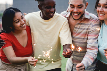 Diverse friends having fun celebrating with fireworks - Focus on sparklers