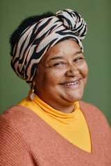 Vertical close up portrait of black senior woman wearing ethnic prints and smiling at camera...