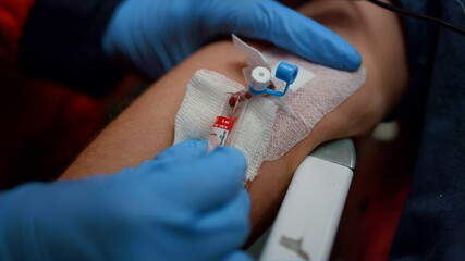 Doctor taking blood from man vein into tube. Paramedic providing blood test 