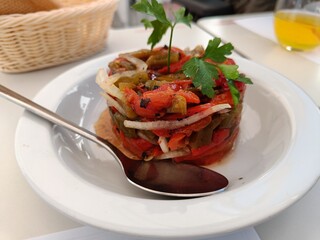 Vegetables salad on white plate. Red and yellow sweet peppers grilled with garlic and basil.Mediterranean cuisine.