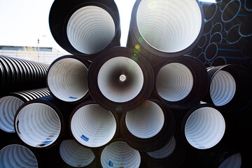 Plastic pipes production plant warehouse. Black and white PVC channelled pipes.