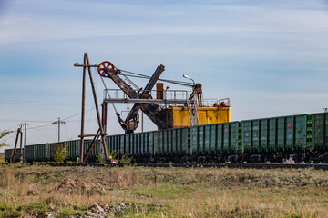 Ore loading station. Excavator loads open wagons. Bridge and wood electric pole. Desert sand and grass. Khromtau, Kazakhstan - May 06, 2012: 
