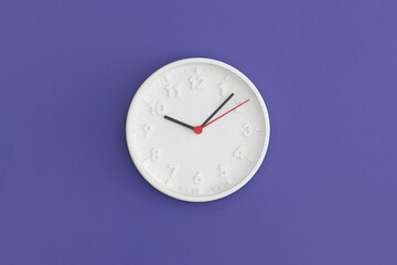 White wall Clock on violet background.