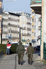 Młode dziewczyny w mundurach wojskowych idą przez miasto. - obrazy, fototapety, plakaty