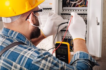 Electrician at work on an electrical panel protected in safety goggles and gloves; Coronavirus....