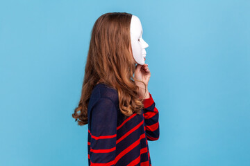 Side view of unknown woman wearing striped casual style sweater, covering her face with white mask,...