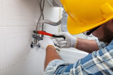 Man plumber working in the bathroom, plumbing repair service, assemble and install concept.