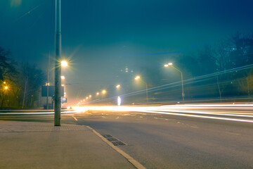 Foggy road with light trails from fast passing cars. Fog over the road with bright yellow lanterns