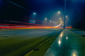 Fog over the road with bright yellow lanterns. Foggy road with light trails from fast passing cars