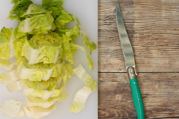 Lechuga fresca, picada en una tabla de cortar, cuchillo verde, vista superior