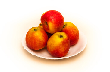 Red apples on a white plate on a white background