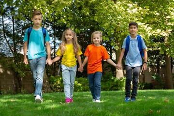 Fototapeta premium Group of happy school child with schoolbag in outdoor park