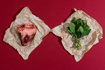 Creative flat lay of a real animal heart meat and spinach on craft paper and red burgundy...