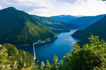 Fototapeta na wymiar Bridge over Lake Piva located in a canyon between high green mountains near Pluzine. Montenegro.