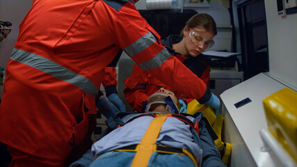 Mixed race paramedics taking care about patient in emergency vehicle