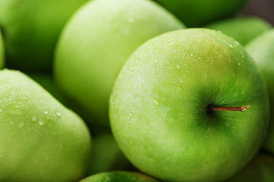 Ripe fruit of a green apple in close-up with dew drops.
