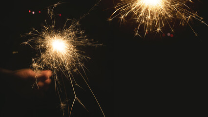 Burning sparkler at night. Hand holds a burning sparkler at night. Christmas background with...