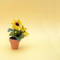 Pot with artificial flowers on a yellow background