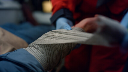 Closeup ambulance paramedic in gloves wrapping patient hand with elastic bandage © stockbusters