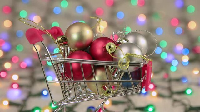 Christmas screensaver balls in a cart on the background of Christmas lights. Copy space. Multicolored lights out of focus. Beautiful footage, video for intro, transition, intro. UHD 4K.
