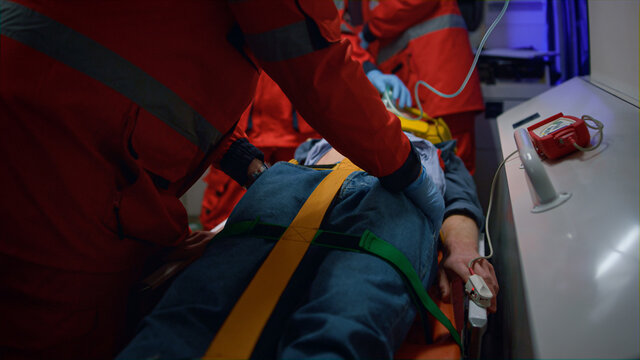Paramedics giving first aid to patient in ambulance car. Doctor examining man 