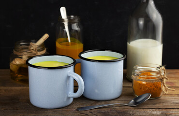 Two cups of golden milk, ayurvedic turmeric beverage and ingredients