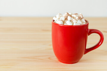 Hot chocolate in red mug with small marshmallows on wooden table. Cocoa in a cup, hot winter drink