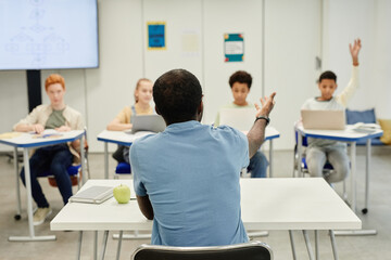 Back view shot of African-American teacher working with diverse group of children, copy space