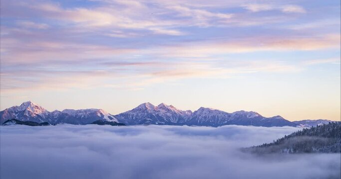 Amazing and dramatic time lapse of cloud inversion. Thick layer of mist moving in alpine valley in Slovenia. Sea of cloud with mountain tops rising out of the fog. Aerial view. Winter season. Sunrise