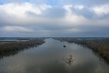 The Loire and its vegetation in Europe, in France, in the Center region, in the Loiret, towards Orleans, in Winter, during a cloudy day.