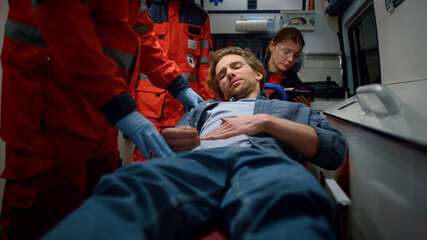 Emergency care assistants examining patient in ambulance car