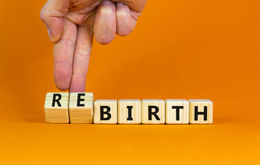 Birth or rebirth symbol. Businessman turns wooden cubes and changes the word birth to rebirth. Beautiful orange table orange background, copy space. Business, birth or rebirth concept.