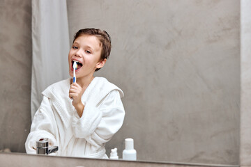 boy brushing his teeth in bathroom. Smiling caucasian kid in bath room. Washbasin, clean teeth. Restroom in home interior. Health care. Children and toothbrush, toothpaste. Dental health