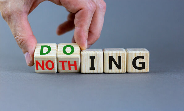 Doing or nothing symbol. Businessman turns wooden cubes and changes the word Nothing to Doing. Beautiful grey background, copy space. Business, doing or nothing concept.