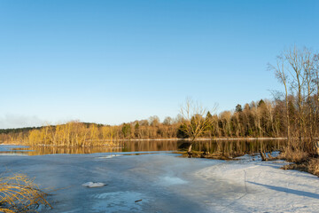 Spring melting of ice and snow on the river on a sunny evening. Trees and shrubs are flooded areas. Landscape of spring nature on the river flood