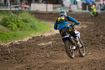Fototapeta na wymiar Unrecognized athlete riding a sports motorbike and muddy wheel on a motocross racingt